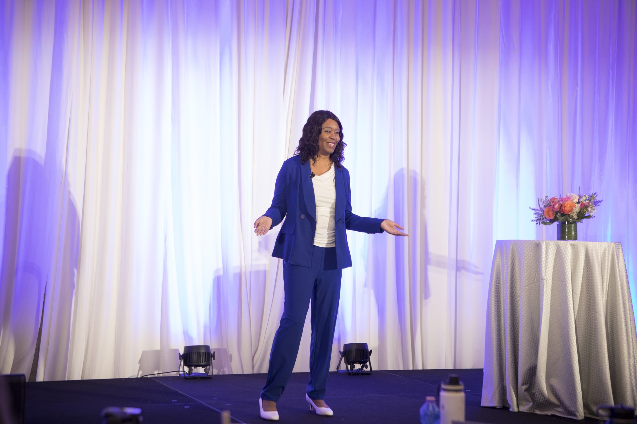 Alexis King speaking to an audience on a lit conference stage