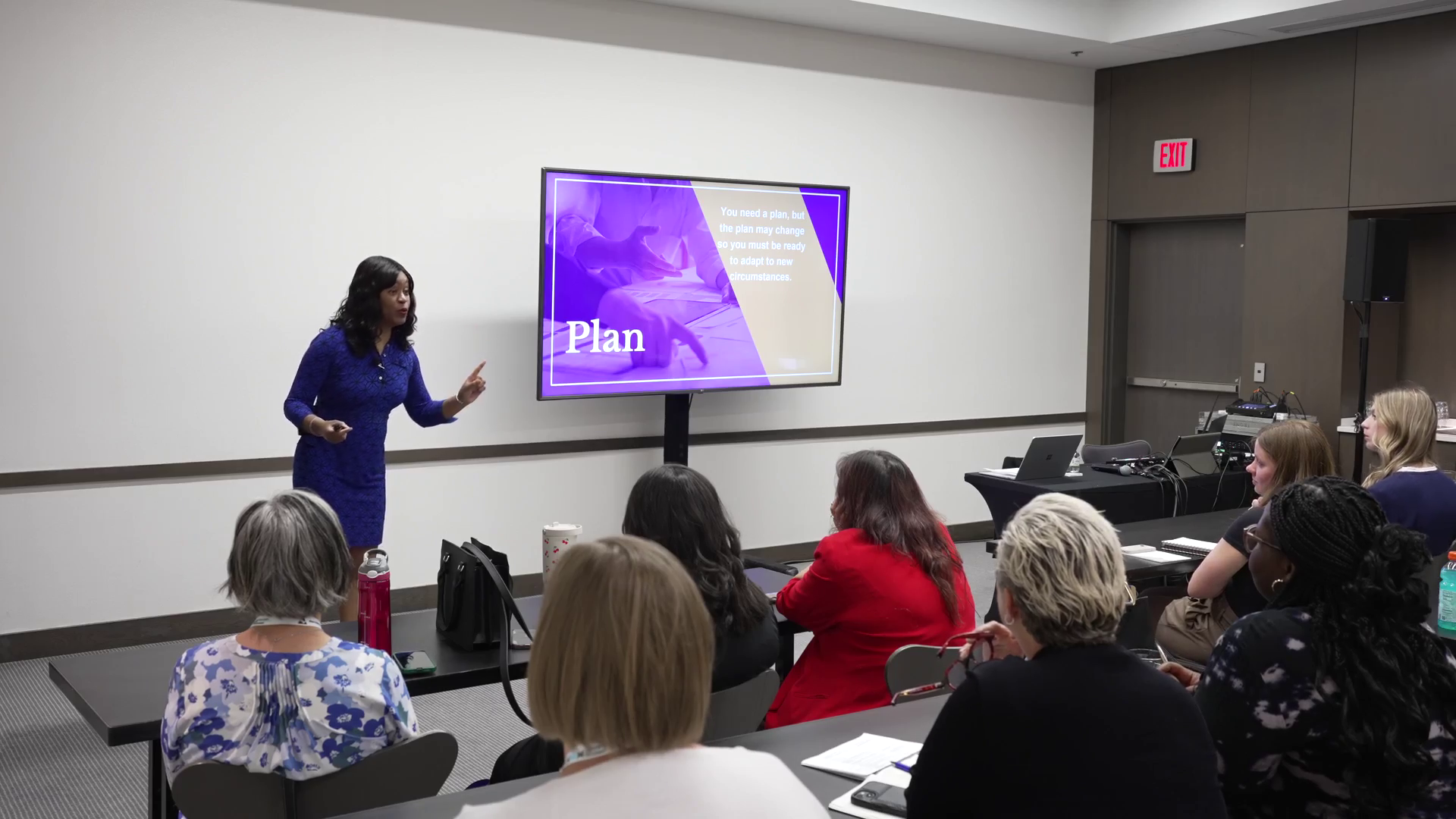 Alexis King speaking to a seated audience with a presentation slide behind her